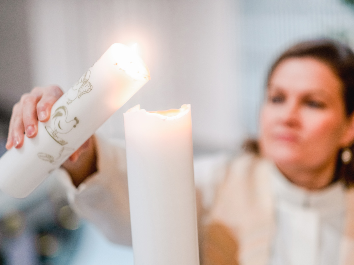En präst tänder ett ljus med hjälp av ett annat ljus.