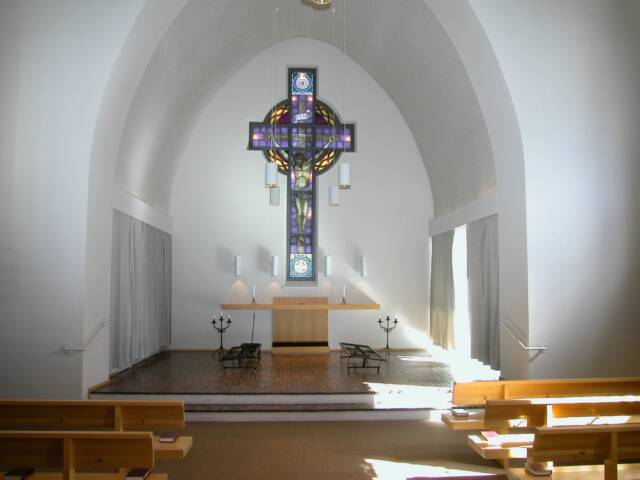 Ahveniston kappelin alttari ja Kristusta ristillä esittämä Ilmari Launiksen tekemä lasimaalaus.
